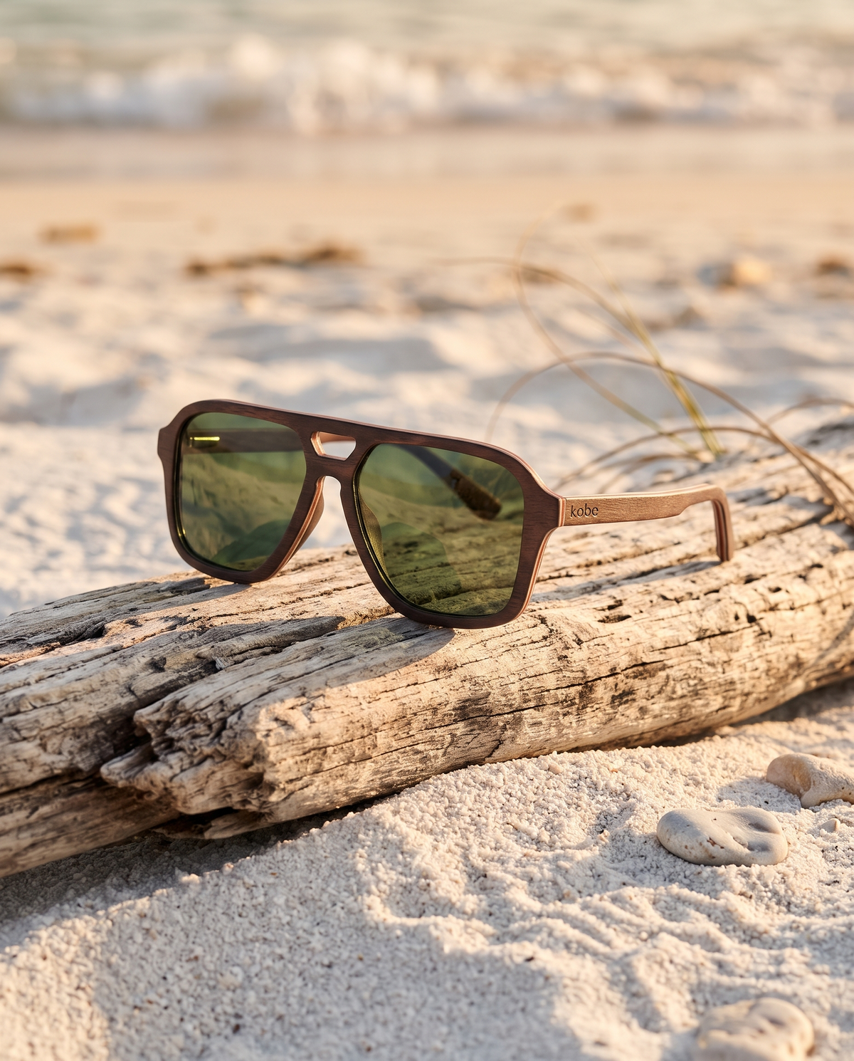 Pablo Walnut sunglasses by Kobe Afrika resting on driftwood on a white sand beach