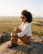 Woman sitting on a rock above the savanna in Agave Brown sunglasses by Kobe Afrika