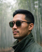 Man wearing Arashi Walnut sunglasses by Kobe Afrika in a bamboo forest, close-up