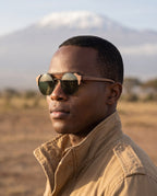 Man wearing Atacama Walnut sunglasses by Kobe Afrika below Kilimanjaro, close-up