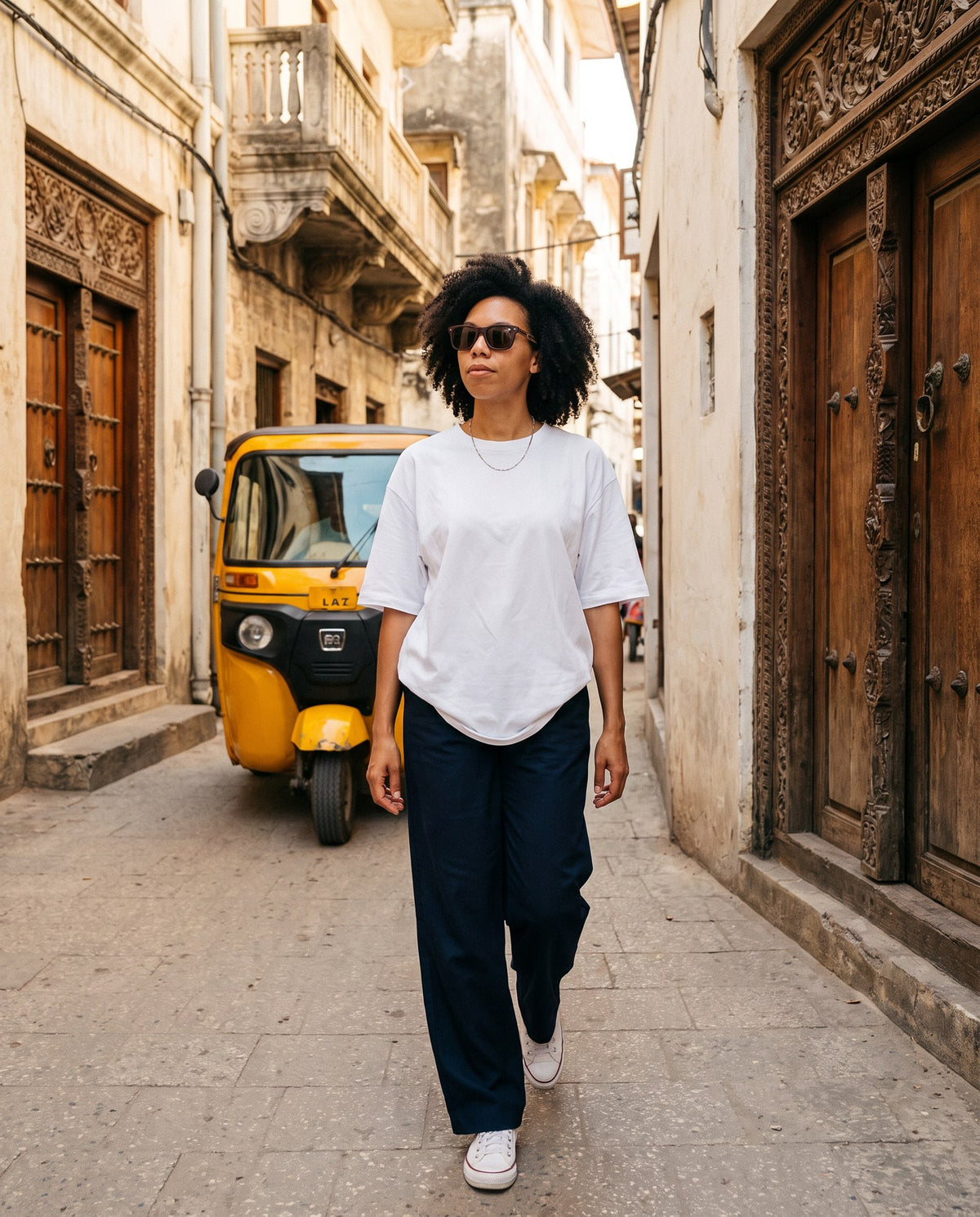 Woman walking an old-town street in Borneo Skate Blue sunglasses by Kobe Afrika