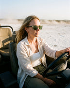 Woman driving across a salt flat in Chalbi Green sunglasses by Kobe Afrika