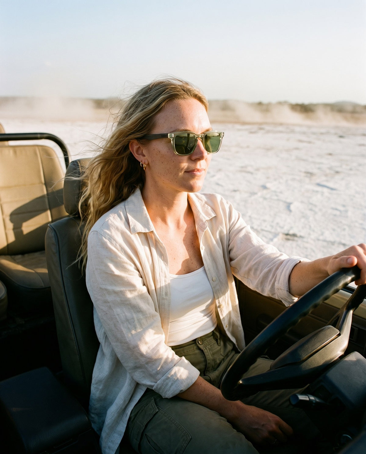 Woman driving across a salt flat in Chalbi Green sunglasses by Kobe Afrika