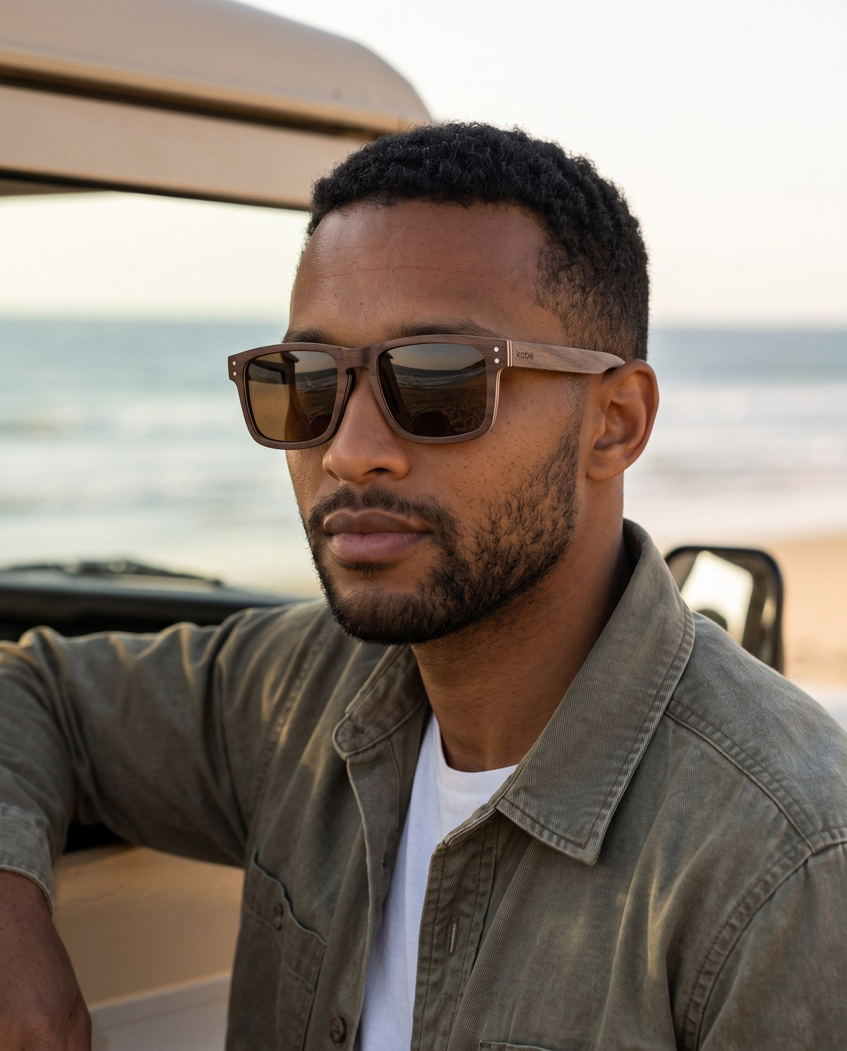 Man wearing Fraser Walnut sunglasses by Kobe Afrika on a beach drive, close-up