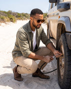 Man checking tyre pressure on a beach drive in Fraser Walnut sunglasses by Kobe Afrika