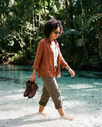 Woman wading through a rainforest creek in Fraser Walnut sunglasses by Kobe Afrika
