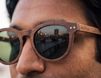 Close-up of Java Walnut sunglasses by Kobe Afrika on a man, showing the wood grain and lens