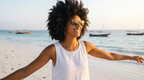 Woman on the beach with dhows offshore in Java Walnut sunglasses by Kobe Afrika