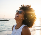 Woman laughing on the beach at sunset in Java Walnut sunglasses by Kobe Afrika, close-up