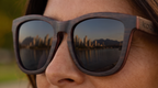 Close-up of Namib Ebony sunglasses by Kobe Afrika on a woman, skyline in the lens