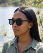 Woman wearing Oahu Ebony sunglasses by Kobe Afrika by a lake, close-up