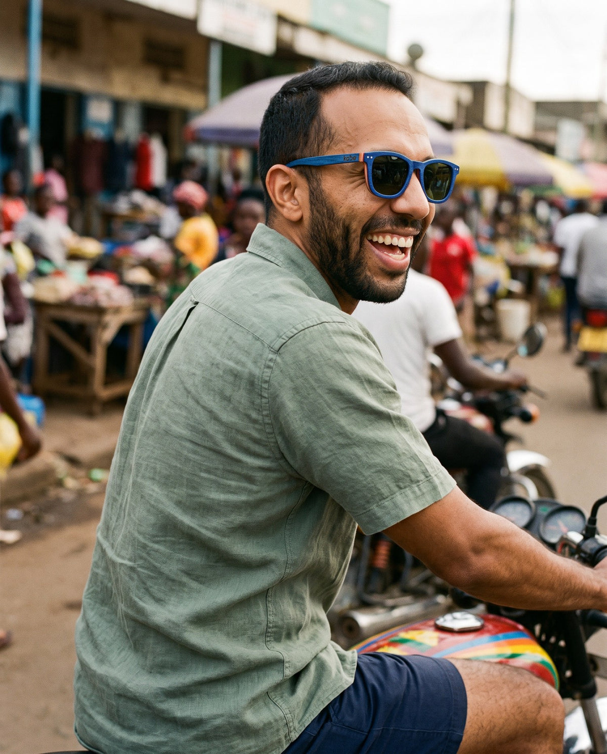 Man on a motorbike through a market in Oahu Skate Blue sunglasses by Kobe Afrika