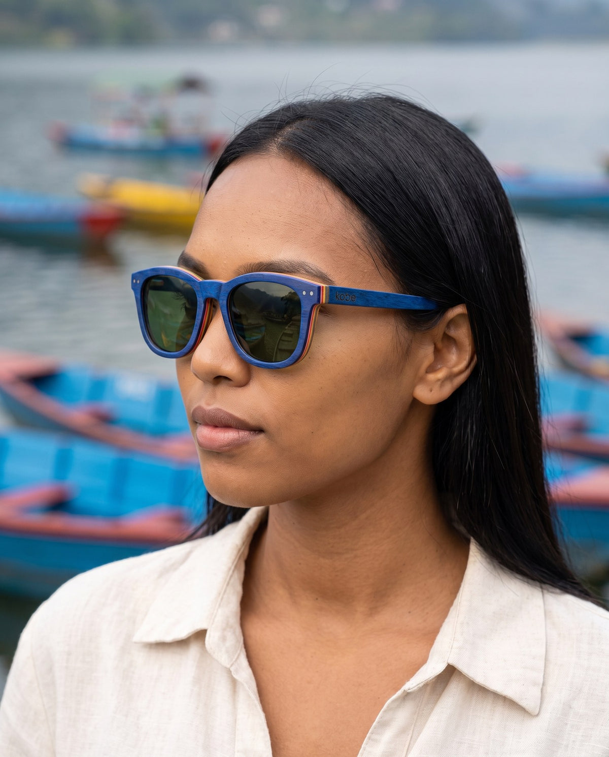 Woman wearing Oahu Skate Blue sunglasses by Kobe Afrika by fishing boats, close-up