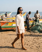 Woman walking past fishing boats on the shore in Oahu Skate Blue sunglasses by Kobe Afrika