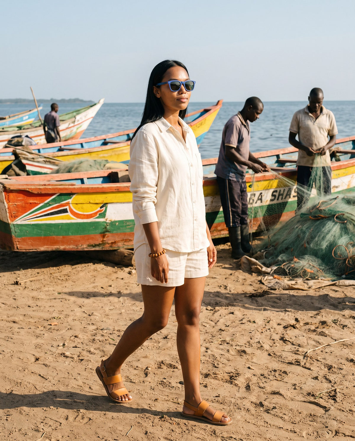 Woman walking past fishing boats on the shore in Oahu Skate Blue sunglasses by Kobe Afrika