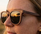 Close-up of Oahu Walnut sunglasses by Kobe Afrika on a woman, savanna in the lens