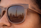 Close-up of Sahara Walnut sunglasses by Kobe Afrika on a woman, skyline in the lens